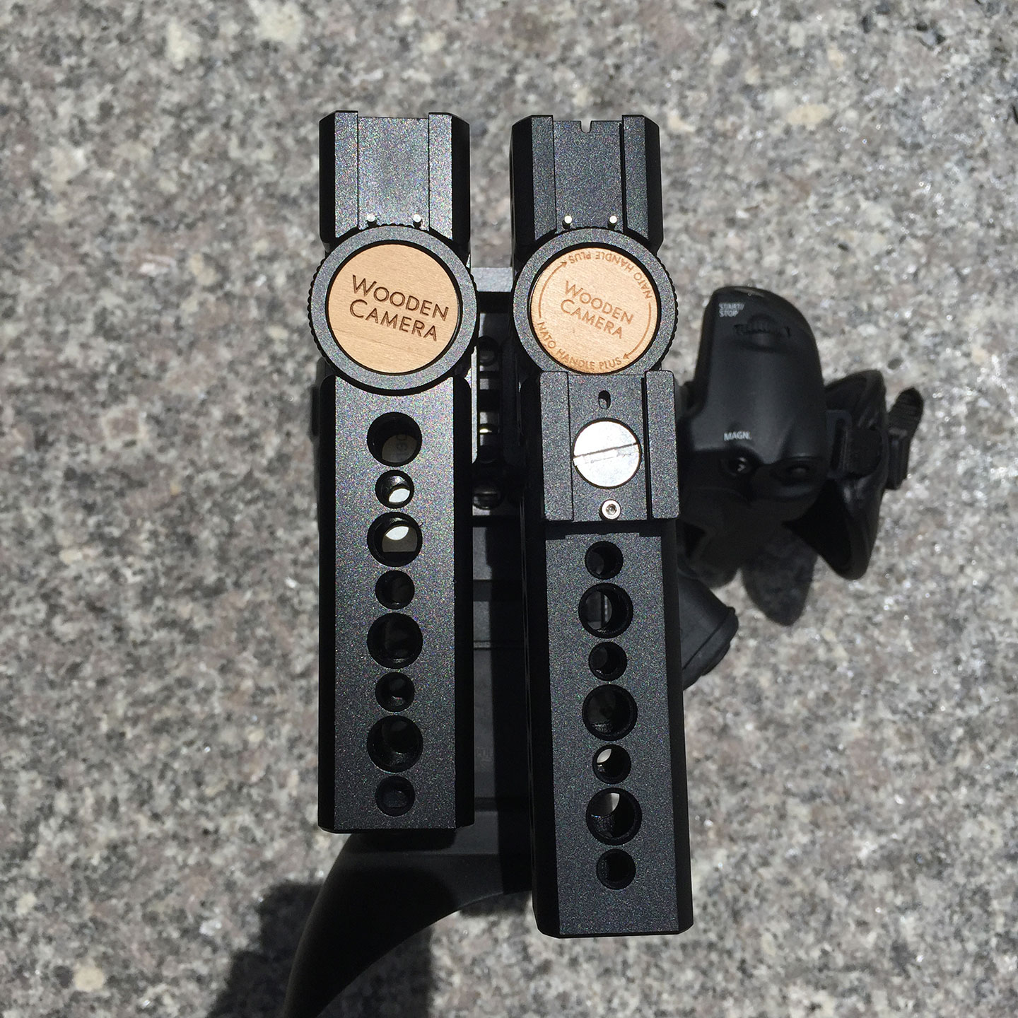 Top view of a Wooden Camera NATO Handle (Plus) old vs. new version. The new version has an Universal Hot Shoe mounted via guide pin in in the Arri style ⅜" hole.